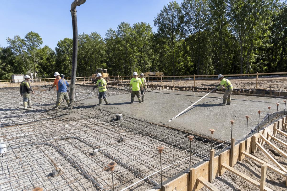 Crew placing and screeding a reinforced concrete slab on grade