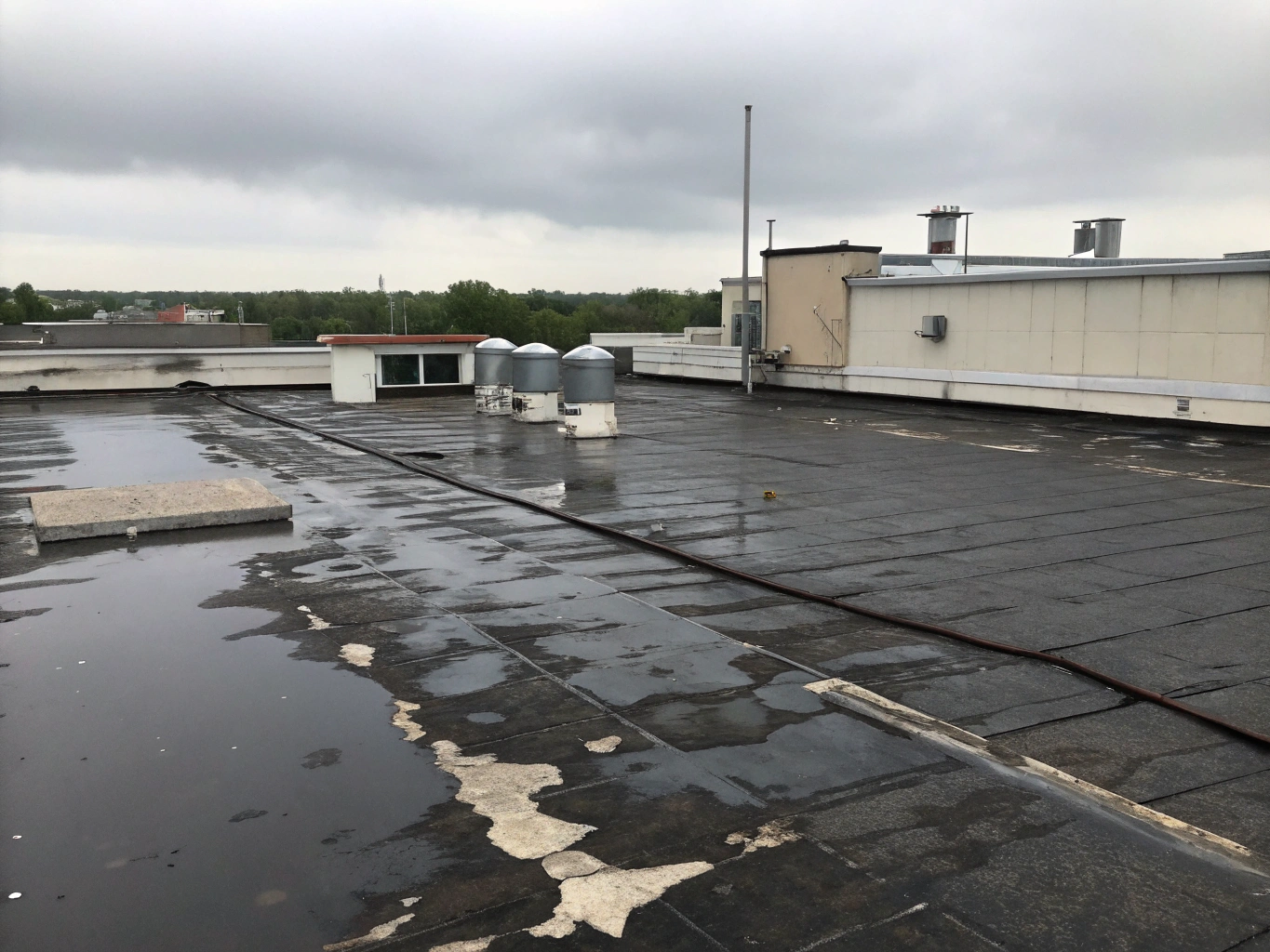 Worn flat roof with ponding water and cracked asphalt before retrofit
