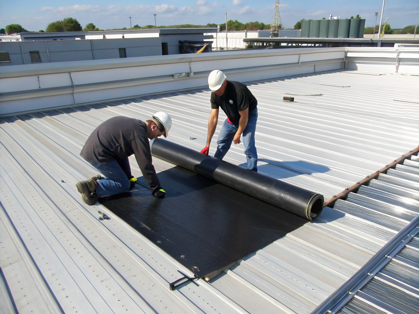 Commercial roofing crew heat welding seams on a flat roof system